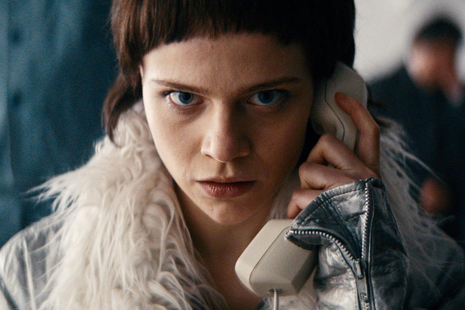 Eine Frau mit ernstem Blick telefoniert mit einem alten Telefonhörer.