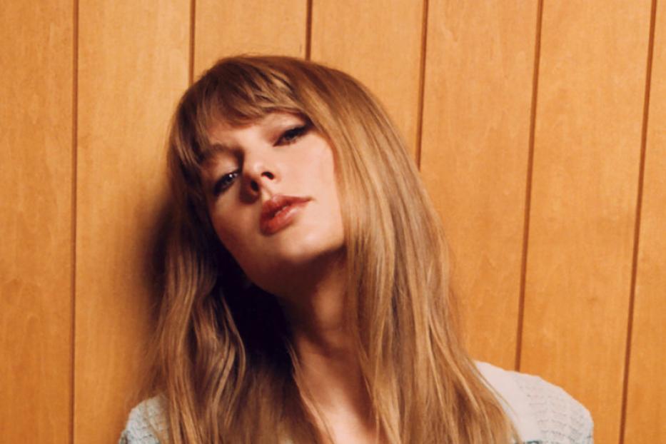 Taylor Swift posiert vor einer Holzwand.