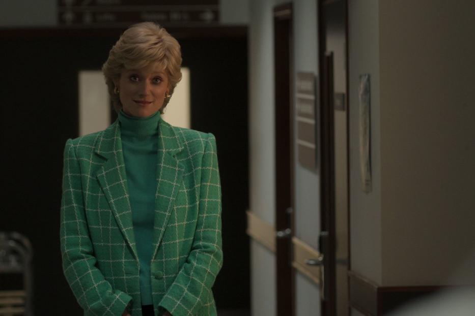 Eine Frau mit blonden Haaren und grünem Blazer steht in einem Flur.