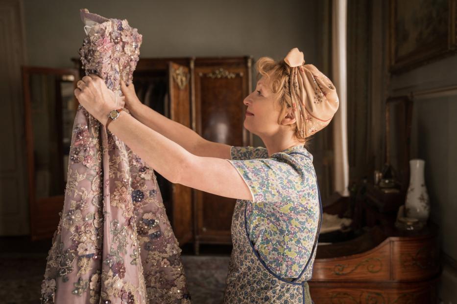 Eine Frau betrachtet ein aufwendig verziertes, hellviolettes Kleid.