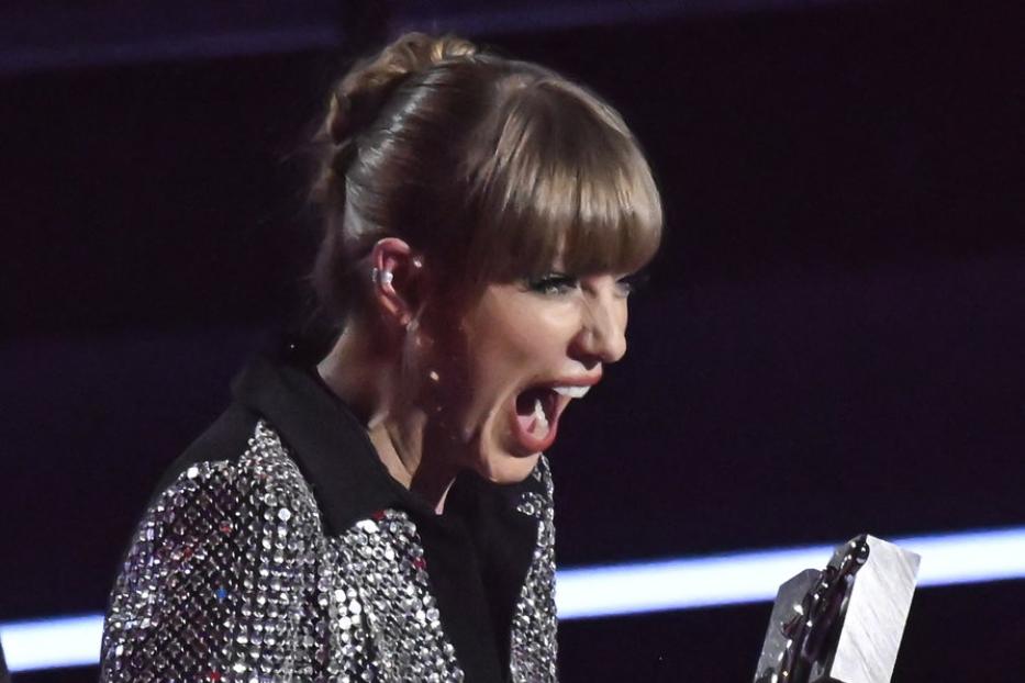 Taylor Swift hält einen Preis in der Hand und schreit vor Freude.