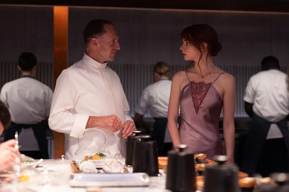 Ein Koch und eine Frau, vermutlich Anya Taylor-Joy, stehen in einer Restaurantküche.
