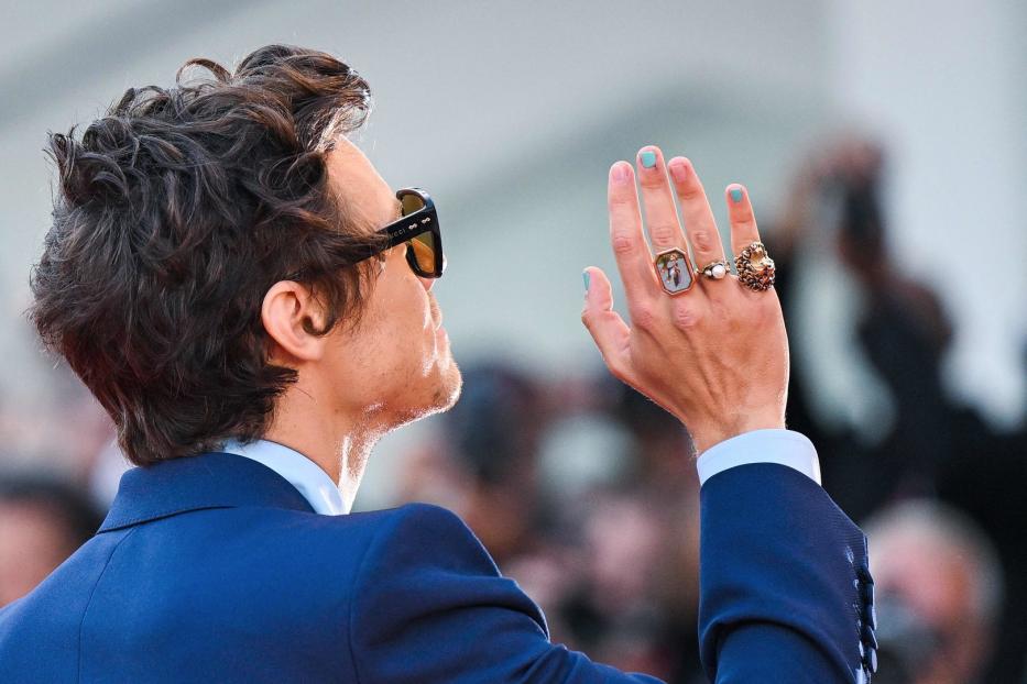 Harry Styles mit Sonnenbrille und mehreren Ringen an der Hand.