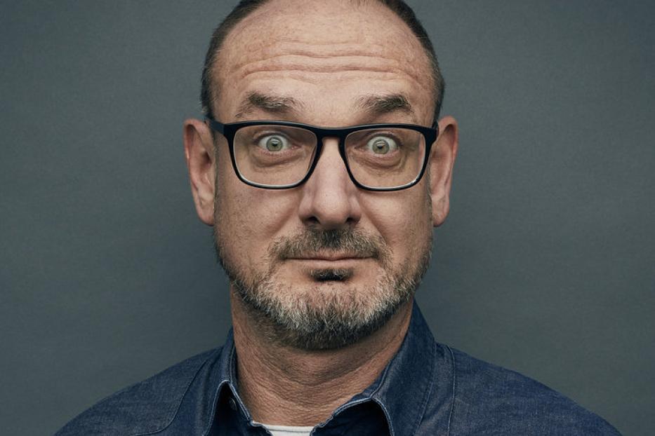 Ein Mann mit Brille und Bart blickt überrascht in die Kamera.