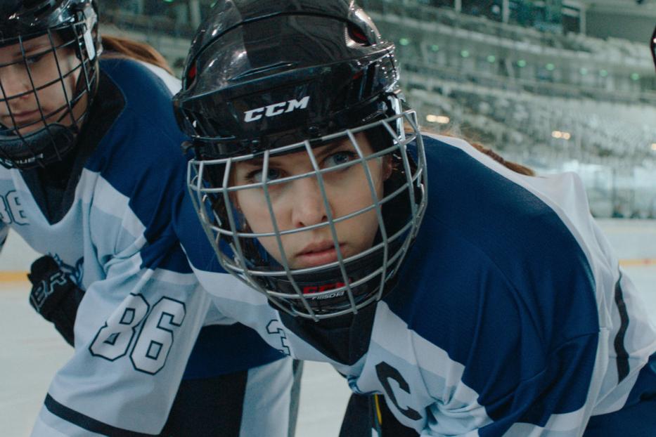 Nahaufnahme von drei jungen Eishockeyspielerinnen mit Helmen und Trikots.