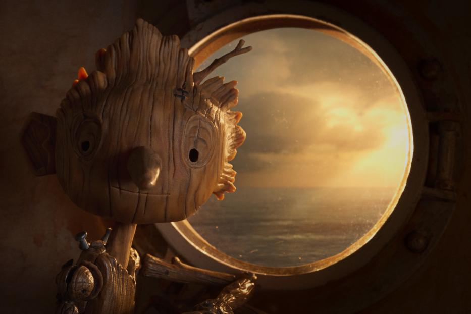 Pinocchio blickt aus einem Bullauge auf das Meer bei Sonnenuntergang.
