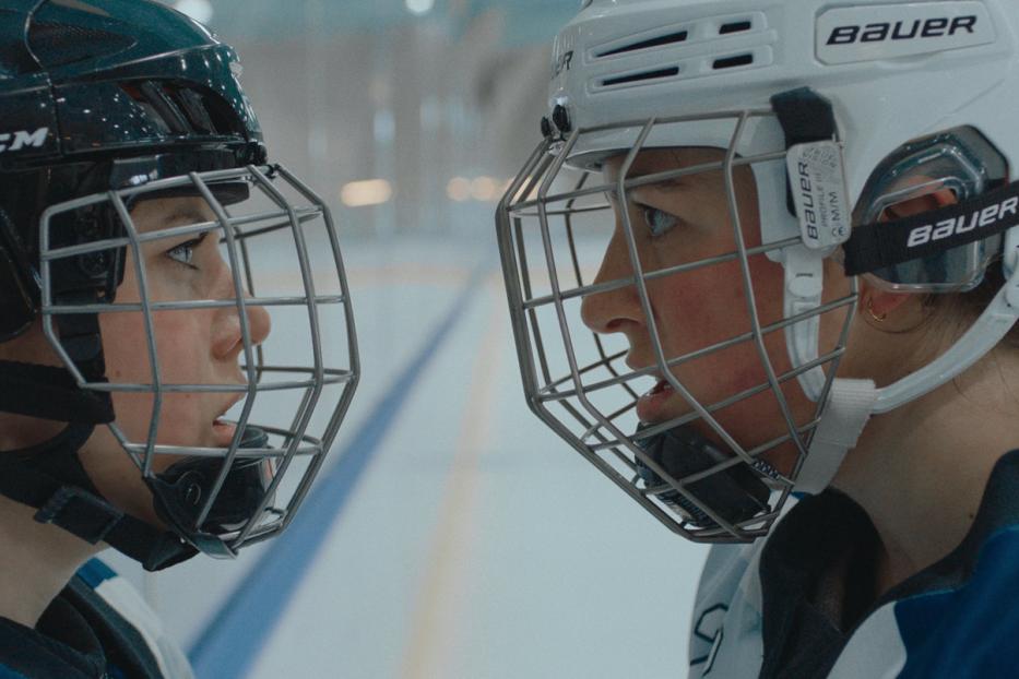 Zwei Eishockeyspielerinnen stehen sich mit Helmen und Visieren gegenüber.
