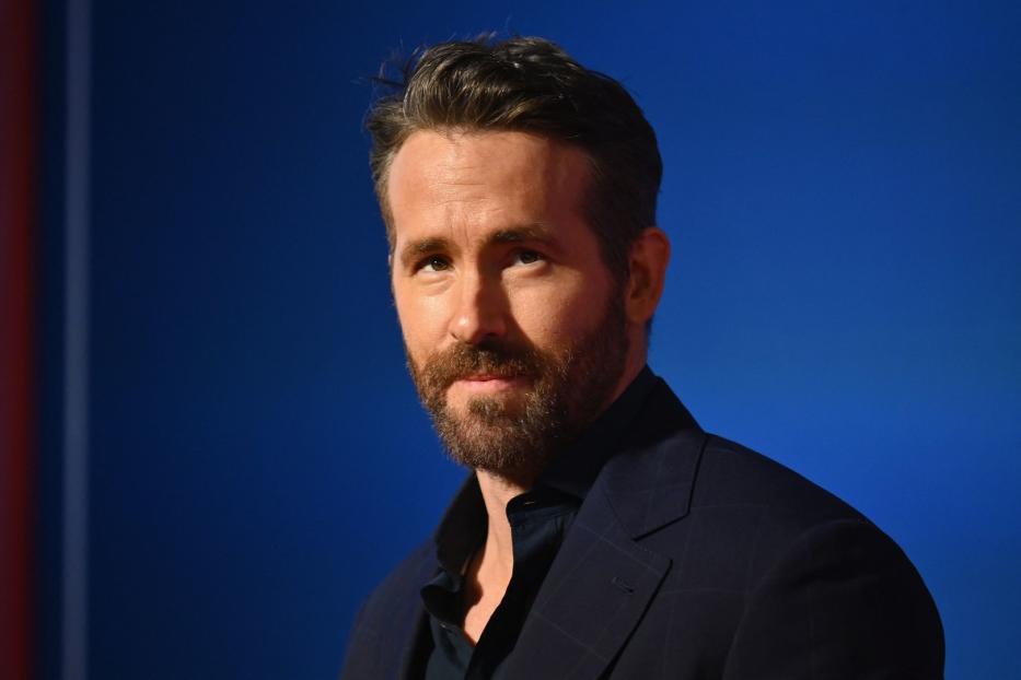 Porträt von Ryan Reynolds vor einem blauen Hintergrund.