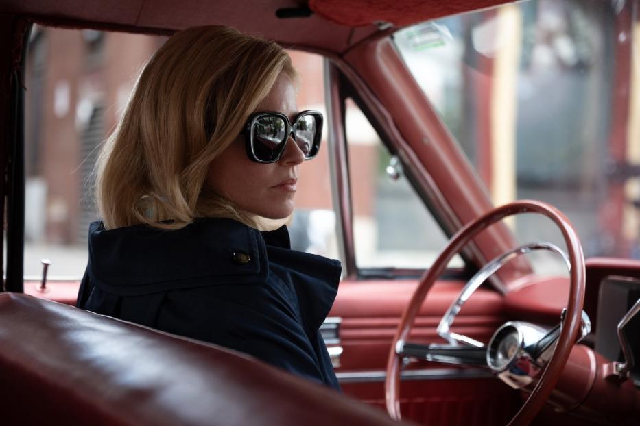 Eine Frau mit Sonnenbrille sitzt in einem roten Oldtimer.