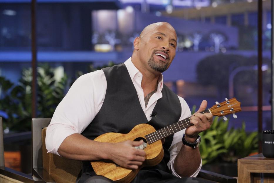 Dwayne „The Rock“ Johnson spielt Ukulele in einem Fernsehstudio.