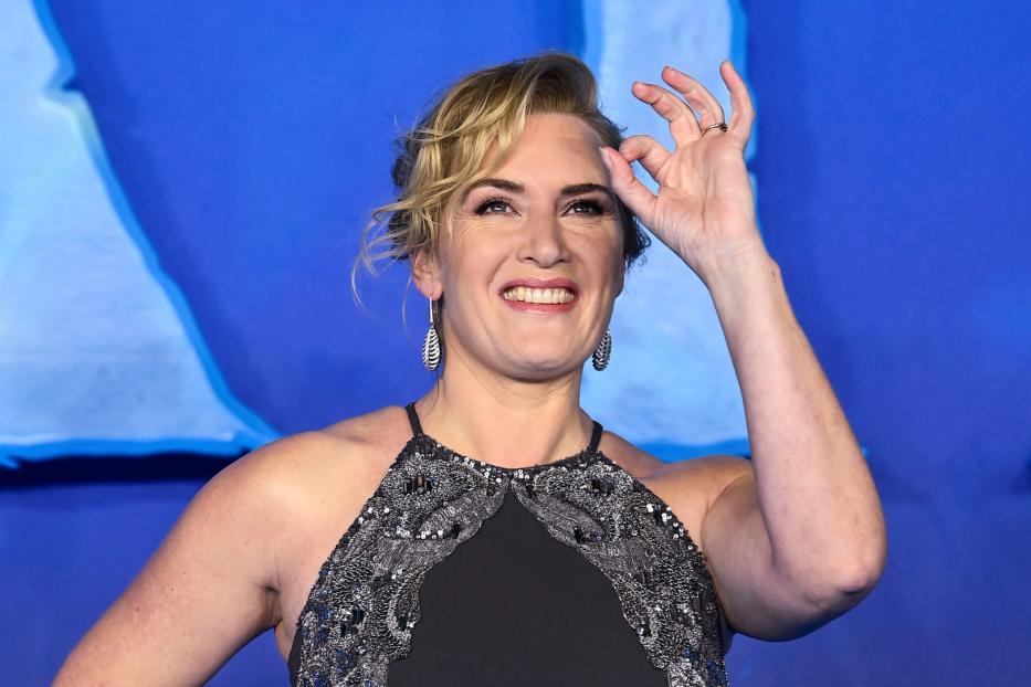 Kate Winslet lächelt und formt mit der Hand eine „Okay“-Geste.