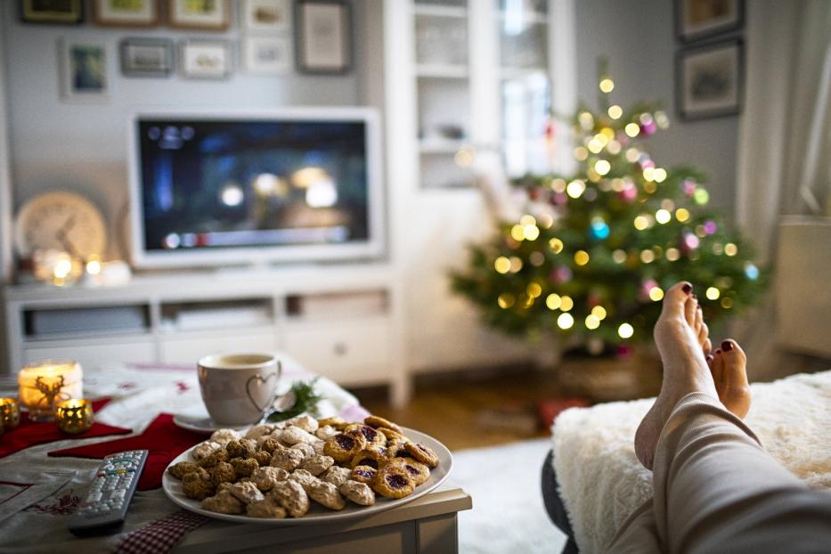 Ein Teller mit Keksen, eine Tasse Kaffee und ein Weihnachtsbaum im Hintergrund.