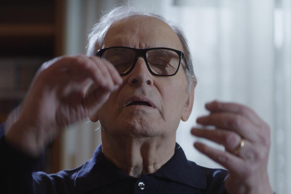 Ein älterer Mann mit Brille gestikuliert mit geschlossenen Augen.