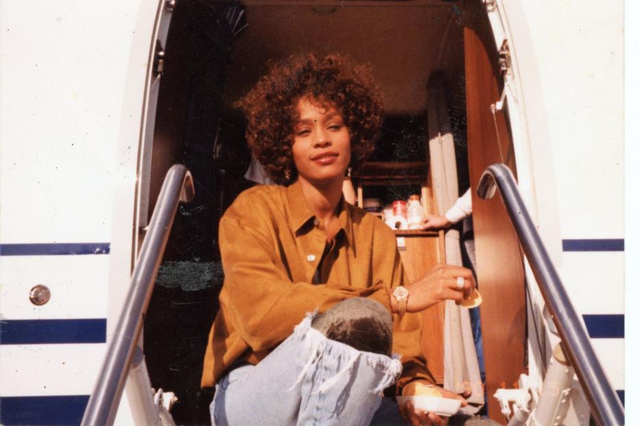 Whitney Houston sitzt auf der Treppe eines Privatjets.