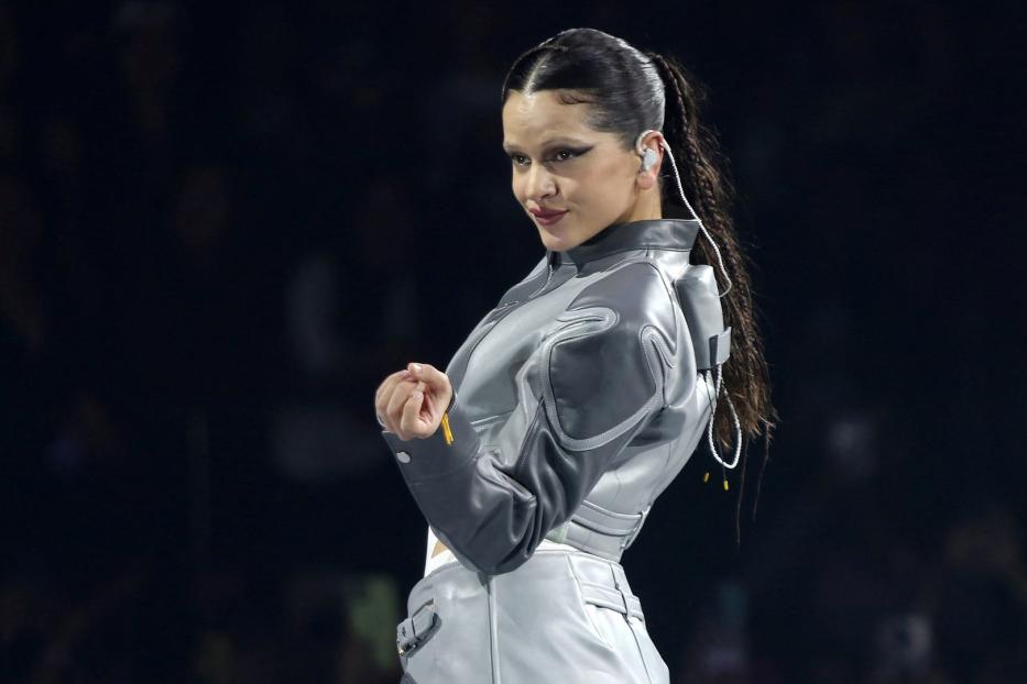 Rosalía trägt eine futuristisch anmutende, grau-silberne Jacke und blickt über ihre Schulter.