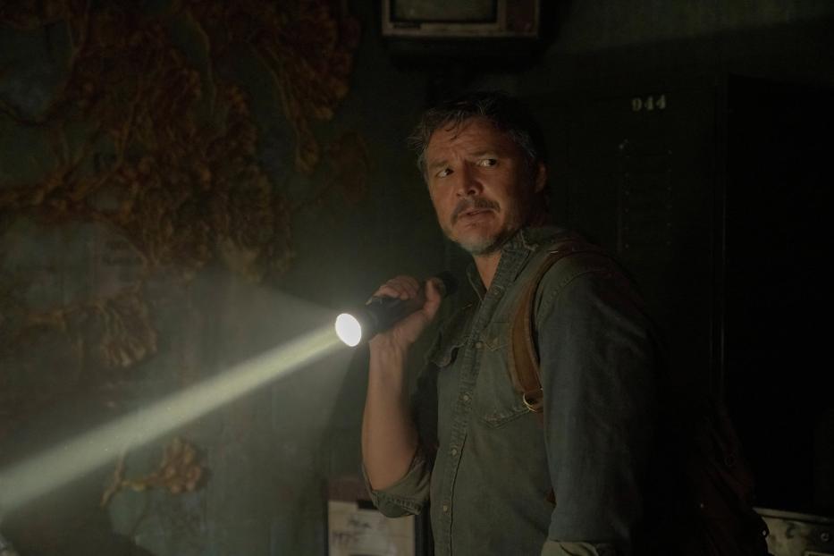 Pedro Pascal als Joel in einer dunklen Szene aus „The Last of Us“, mit einer Taschenlampe in der Hand.