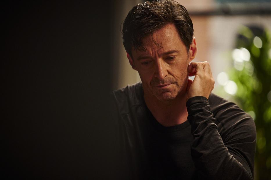 Hugh Jackman wirkt nachdenklich, während er seine Hand an seine Wange hält.