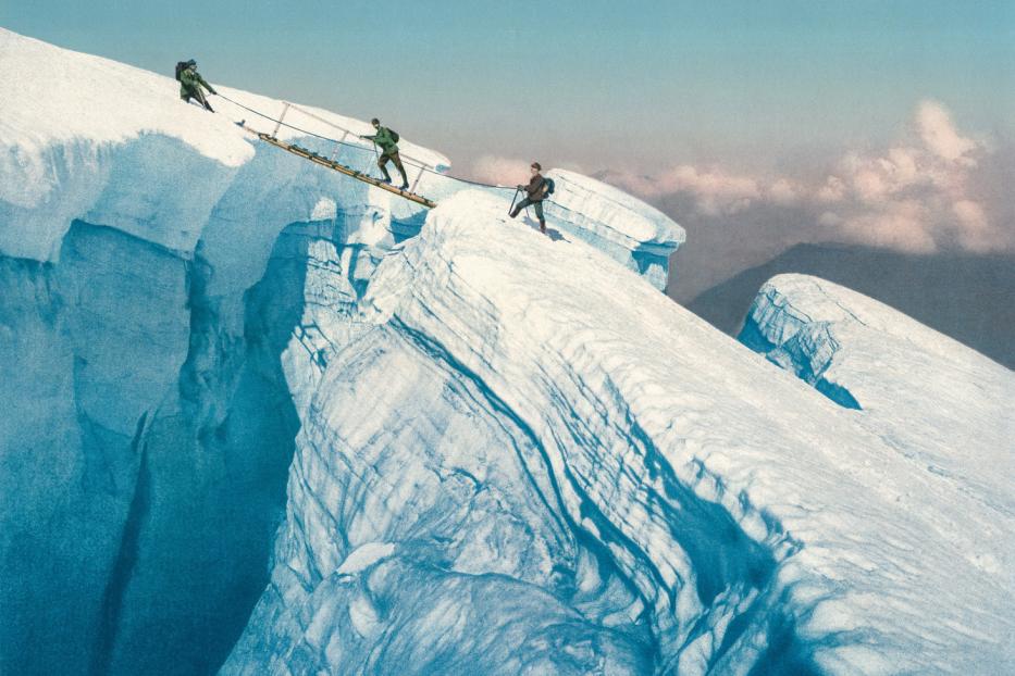 Bergsteiger überqueren eine gefährliche Gletscherspalte mit einer Leiter.