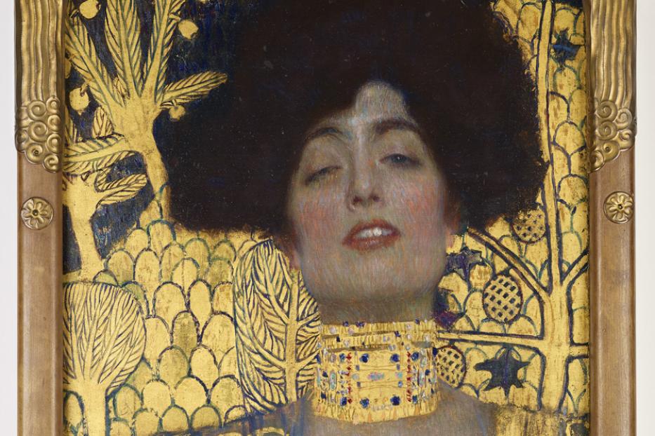 Das Gemälde „Judith I“ von Gustav Klimt zeigt eine Frau mit dunklem Haar und goldenem Schmuck vor goldenem Hintergrund.