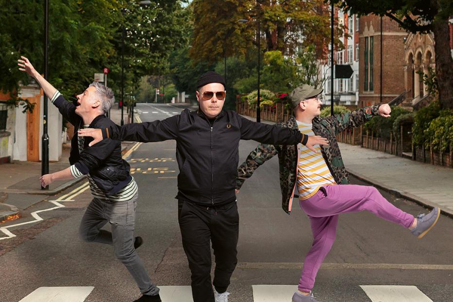 Drei Männer überqueren einen Zebrastreifen und ahmen das Cover von „Abbey Road“ nach.