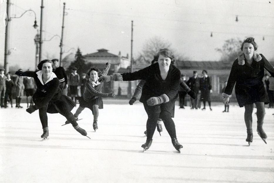 Mehrere junge Frauen laufen auf einer Eisbahn Schlittschuh.