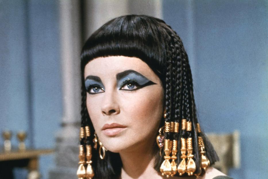 Elizabeth Taylor als Kleopatra mit starkem blauem Augen-Make-up und goldenem Armschmuck.