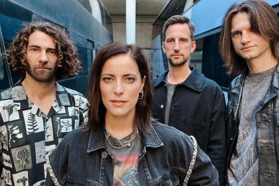 Eine Band posiert vor einem modernen Gebäude für ein Foto.