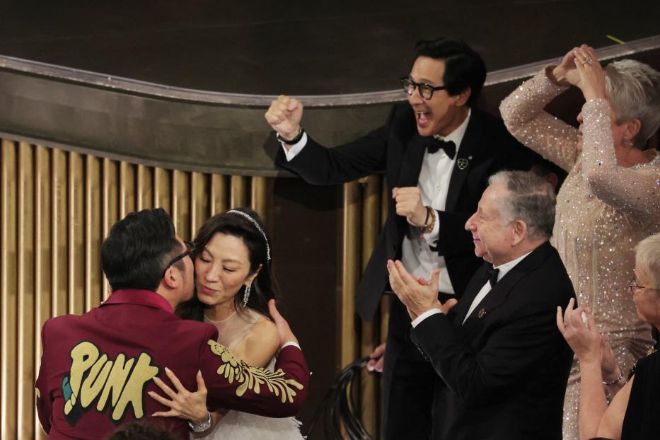 Michelle Yeoh wird nach ihrem Oscar-Gewinn umarmt, während andere applaudieren und jubeln.