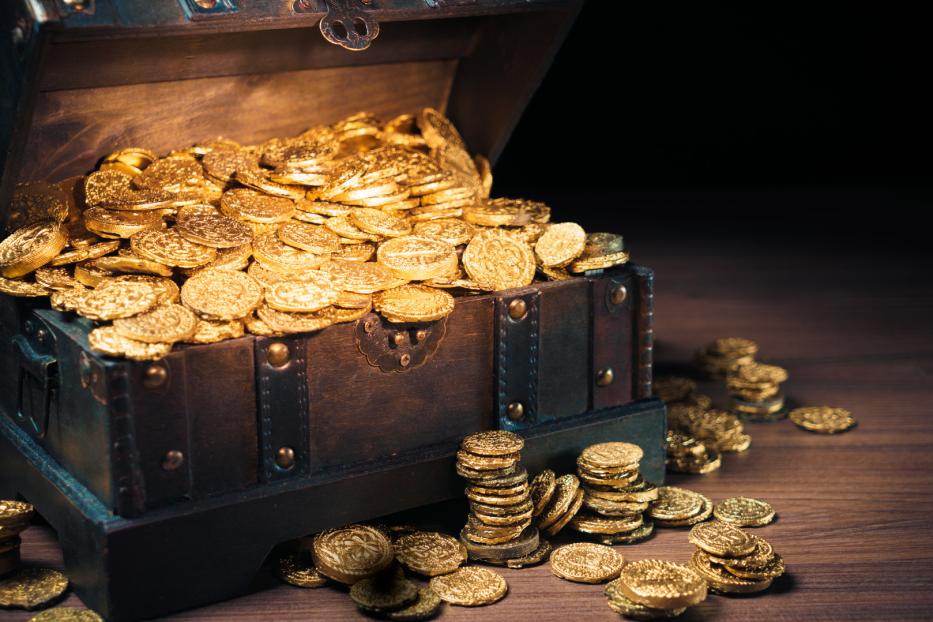 Eine geöffnete Schatztruhe ist mit Goldmünzen gefüllt.