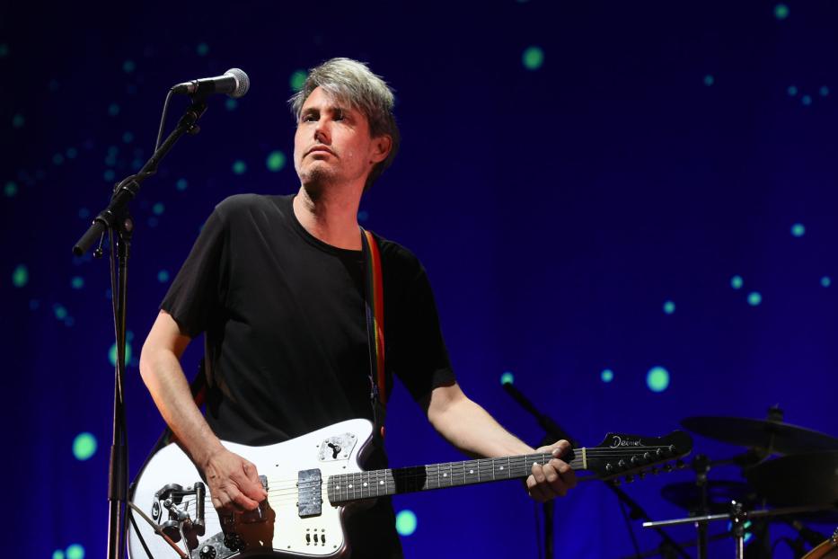 Ein Mann mit grauen Haaren spielt auf einer weißen Deimel Gitarre auf der Bühne.