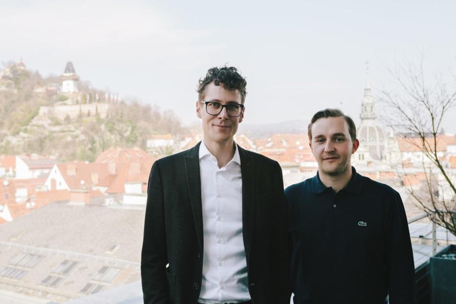 Zwei Männer posieren vor der Skyline von Graz, Österreich.