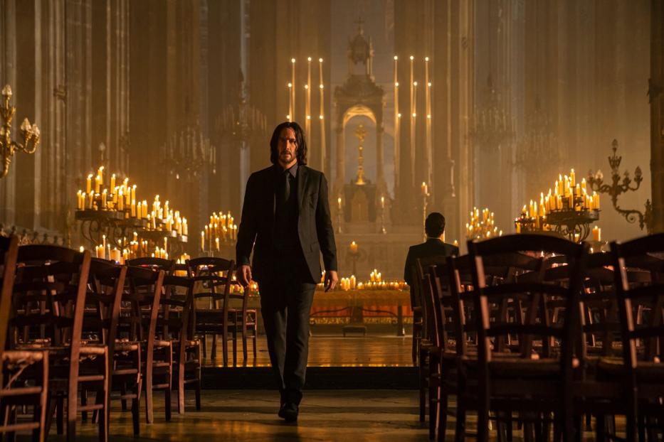 John Wick geht durch eine mit Kerzen beleuchtete Kirche.