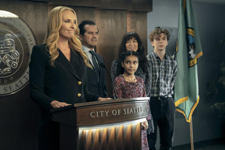 Eine Frau steht an einem Rednerpult mit der Aufschrift „City of Seattle“, umgeben von vier weiteren Personen.