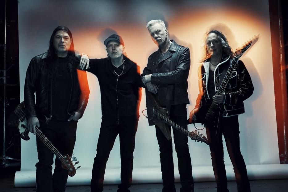 Die Band Metallica posiert mit ihren Instrumenten vor einem weißen Hintergrund.
