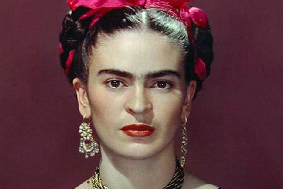 Ein Porträt von Frida Kahlo mit roter Blume im Haar und traditionellem Schmuck.