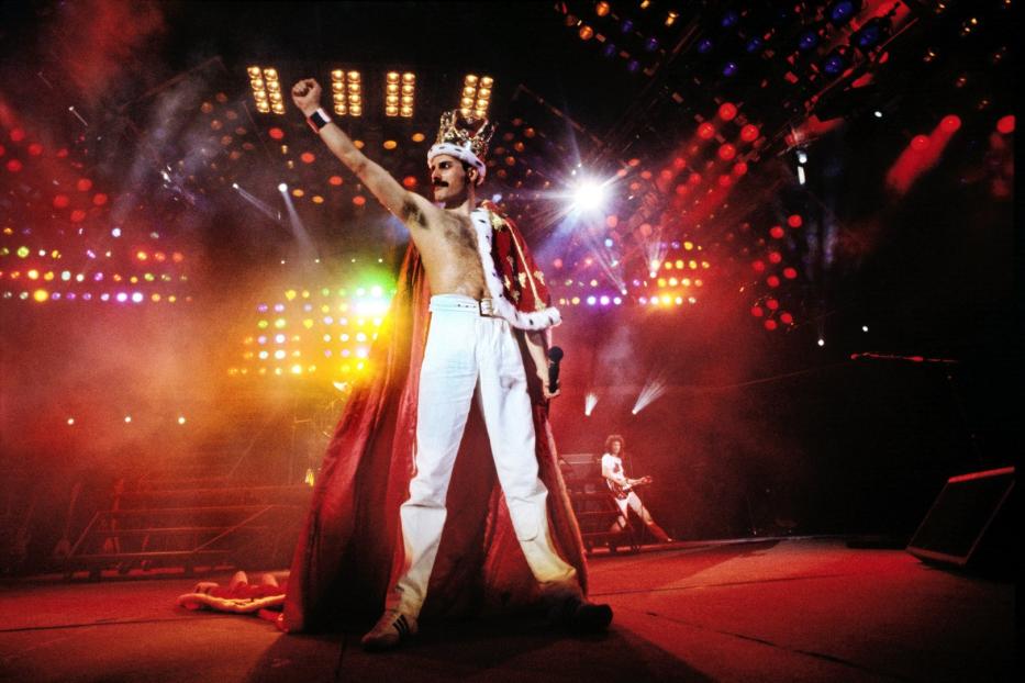 Freddie Mercury von Queen mit Krone und rotem Umhang auf der Bühne.