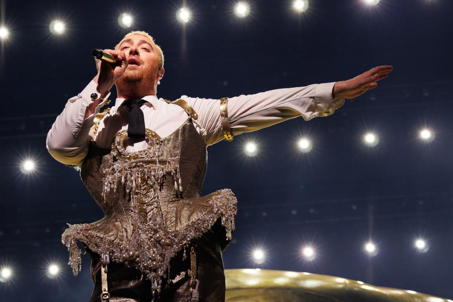 Sam Smith tritt in einem goldenen Korsett und mit Mikrofon auf einer Bühne auf.