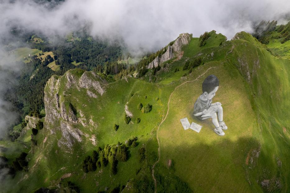 Ein gezeichneter Junge sitzt auf einem grünen Berggipfel und liest in einem Buch.