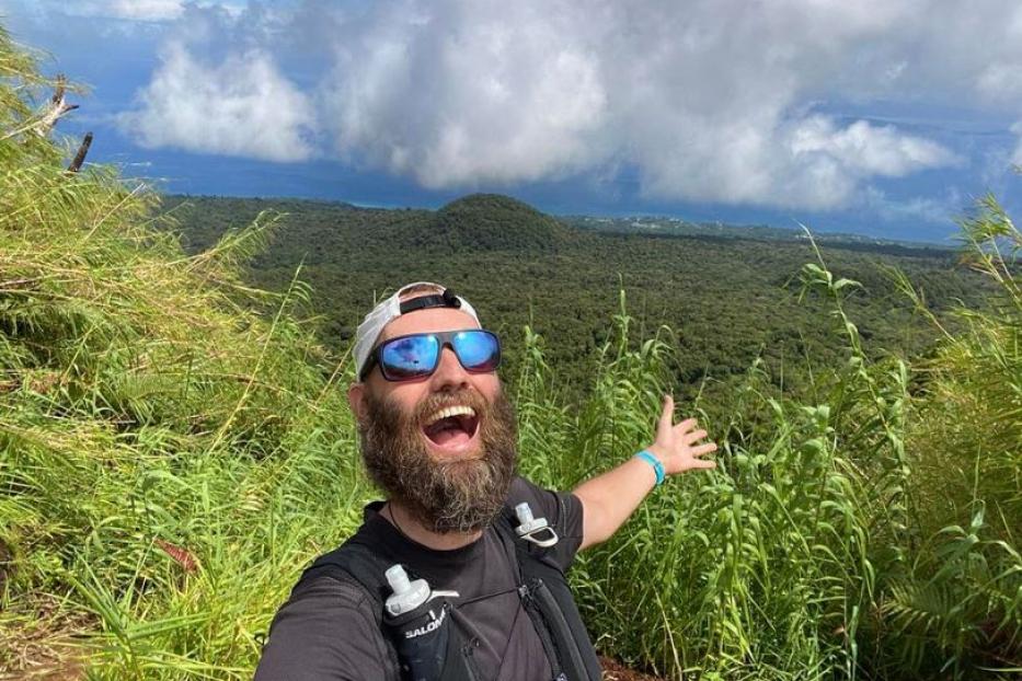 Torbjørn Pedersen steht auf einem Berg mit üppiger Vegetation im Hintergrund.