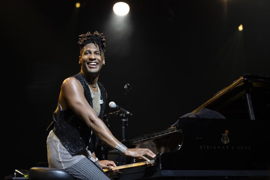 Jon Batiste spielt auf einem Steinway & Sons Klavier und lächelt.
