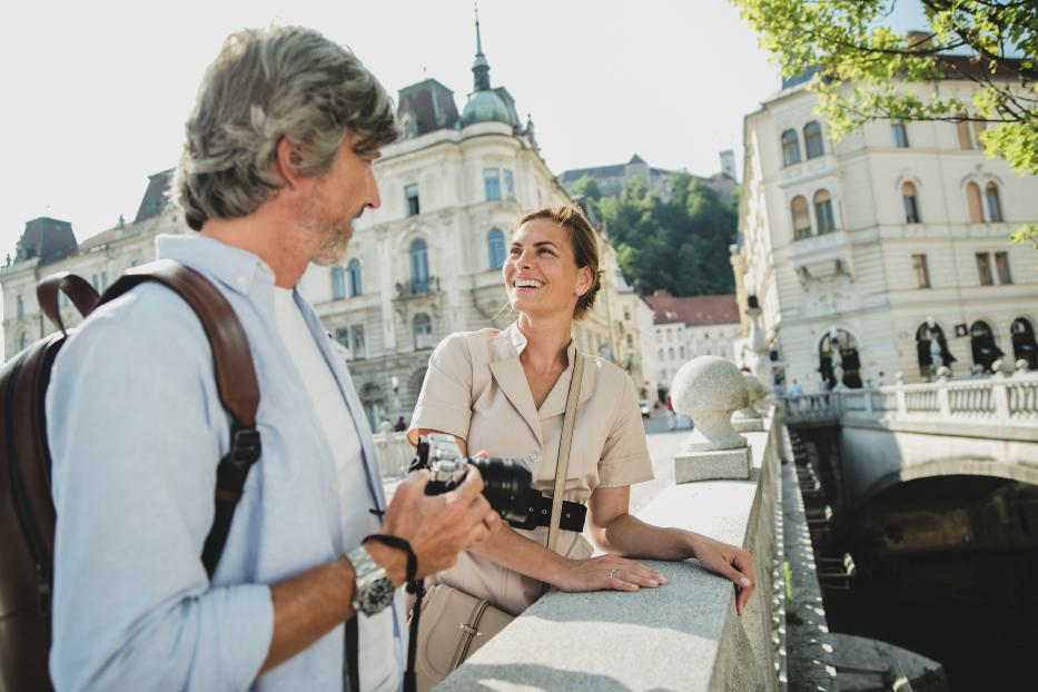 Ein Paar steht auf einer Brücke in Ljubljana, Slowenien, und unterhält sich.