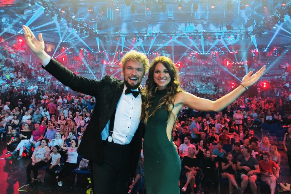 Thommy Ten und Amélie van Tass stehen auf einer Bühne vor Publikum.