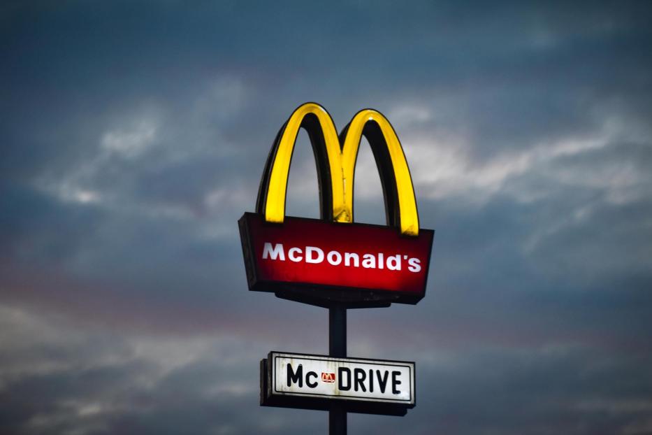 Ein McDonald's-Schild mit dem Schriftzug „McDrive“ vor einem bewölkten Himmel.