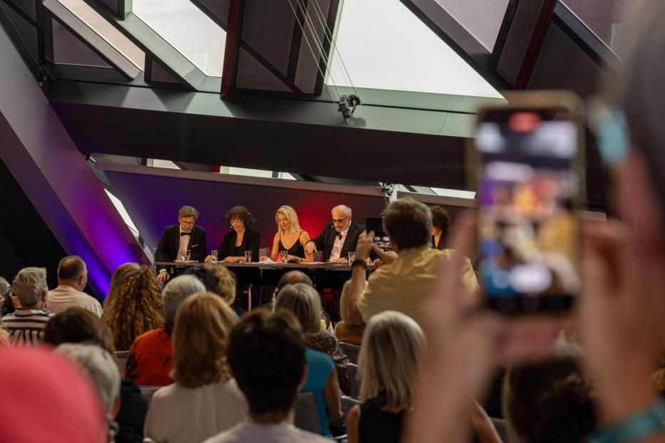 Eine Podiumsdiskussion mit mehreren Personen vor einem Publikum.