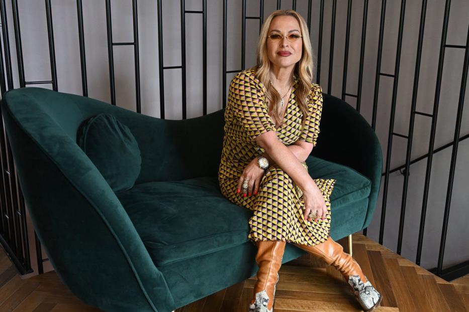 Anastacia sitzt für ein Interview auf einem grünen Sofa.