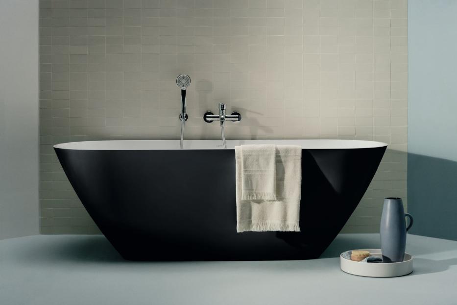 Eine schwarze Badewanne mit einem weißen Handtuch hängt an der Seite.