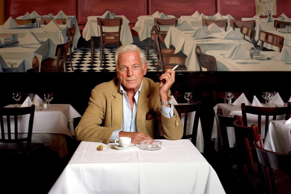 Ein Mann sitzt in einem Restaurant und raucht eine Zigarette.