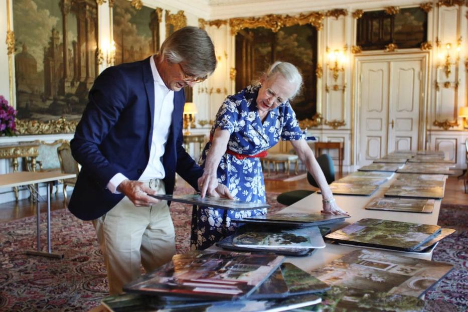 Königin Margrethe II. von Dänemark betrachtet mit einem Mann Landschaftsbilder.