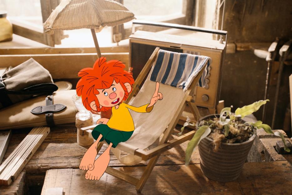 Pippi Langstrumpfs rothaariger Freund sitzt auf einem Liegestuhl in einer Werkstatt.