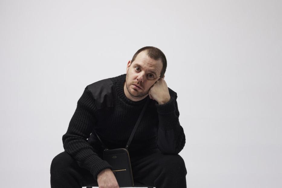Der Rapper Mike Skinner sitzt auf einem Stuhl.